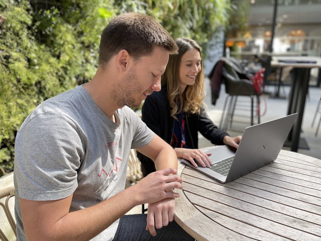 Picture of Alexis and Lili with a laptop smiling in the patio