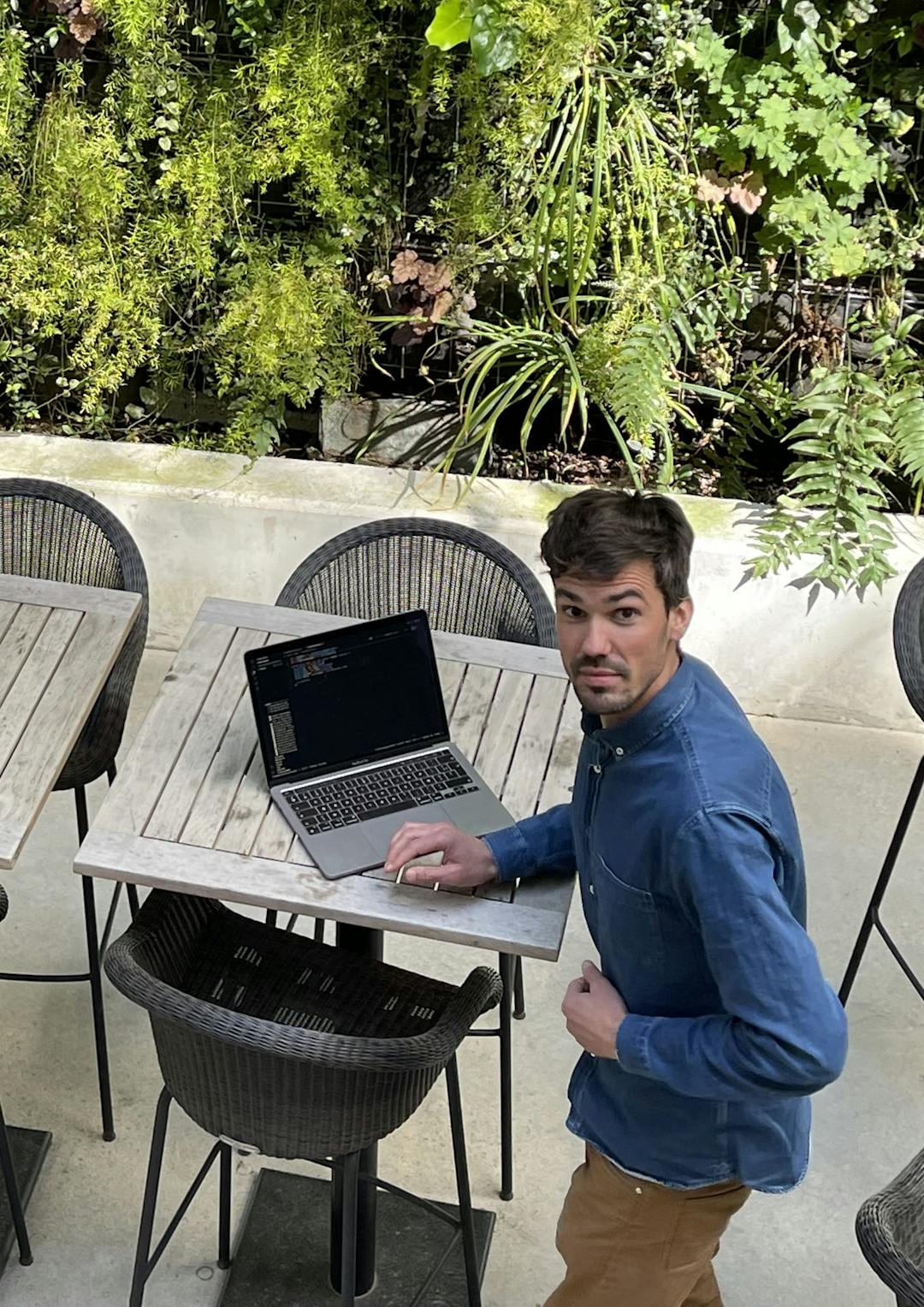 Picture of Nicolas from above in a the patio with a laptop looking surprised
